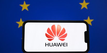 Esta fotografía ilustrativa tomada en Bruselas el 13 de marzo de 2025 muestra el logotipo del gigante chino de las telecomunicaciones Huawei en un smartphone delante de una bandera de la Unión Europea. La policía belga allanó varios domicilios en el país en el marco de una investigación sobre presunta corrupción "bajo la apariencia de lobby comercial", informó la fiscalía. "Varias personas han sido detenidas para ser interrogadas en relación con su presunta implicación en corrupción activa", dijo la fiscalía federal, añadiendo que también se llevaron a cabo registros en Portugal. El periódico belga Le Soir dijo que la investigación estaba relacionada con el gigante tecnológico chino Huawei y sus actividades en Bruselas desde 2021.