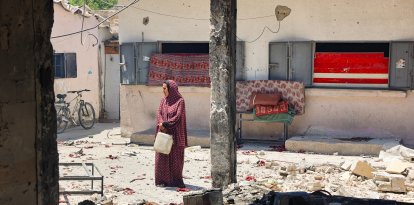 Una mujer lleva un recipiente de plástico en la escuela Mustafa Hafez, en la Franja de Gaza
