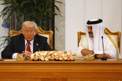El emir de Catar, jeque Tamim bin Hamad al-Thani (d), escucha un discurso del presidente estadounidense, Donald Trump, durante una ceremonia de firma en el Palacio Real de Doha, el 14 de mayo de 2025.