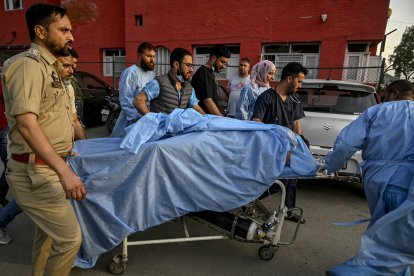 Paramedics and policemen carry an injured tourist after the attack in Kashmir.